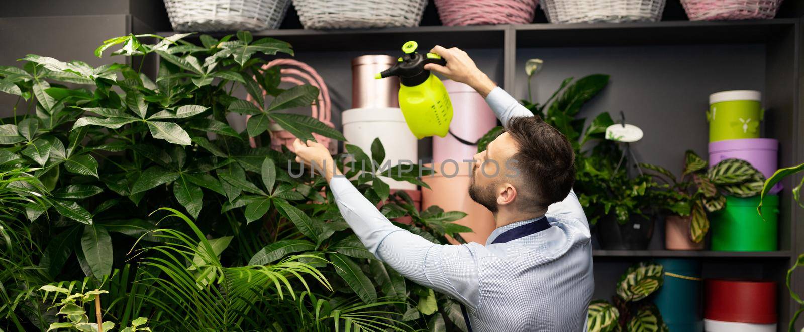 a botanist at a garden center taking care of plants by watering them with a spray bottle.