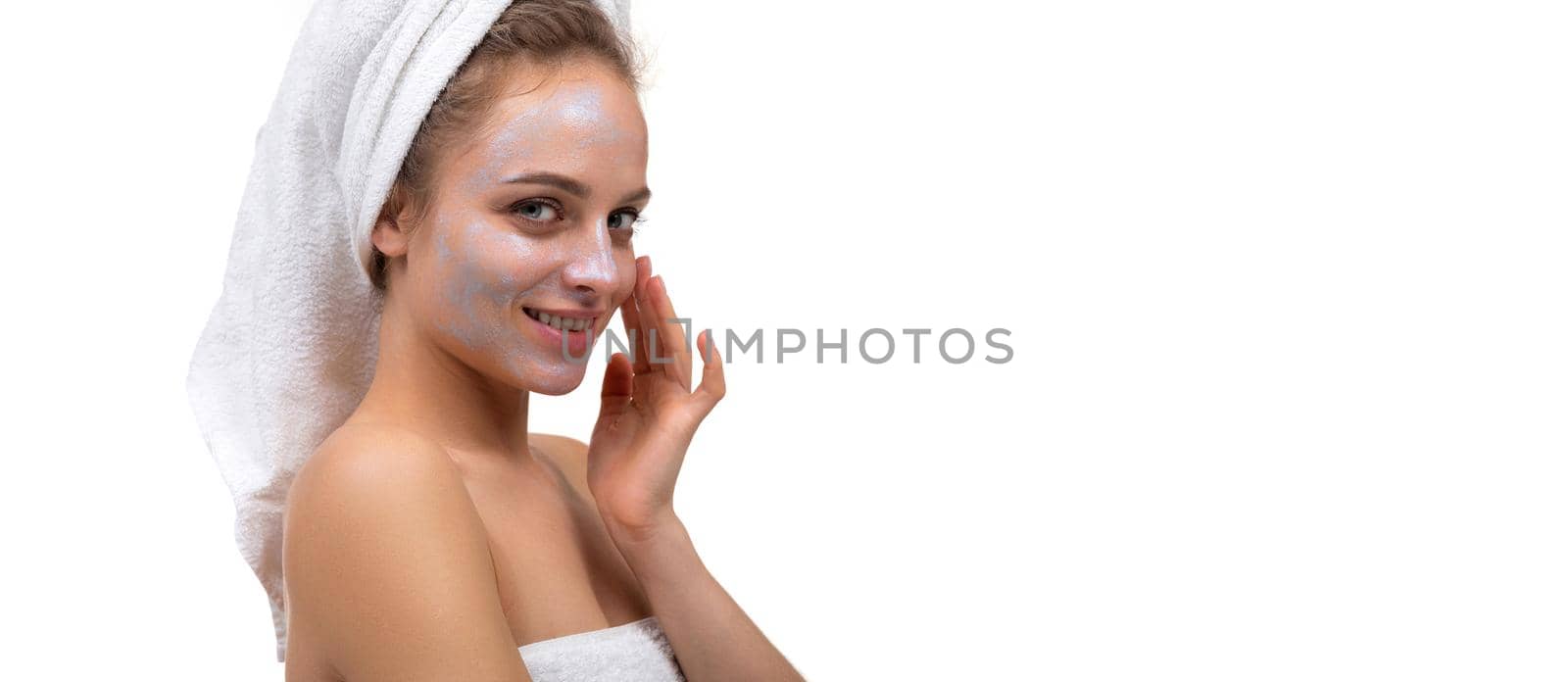 a woman after a shower applies a cream on her face.