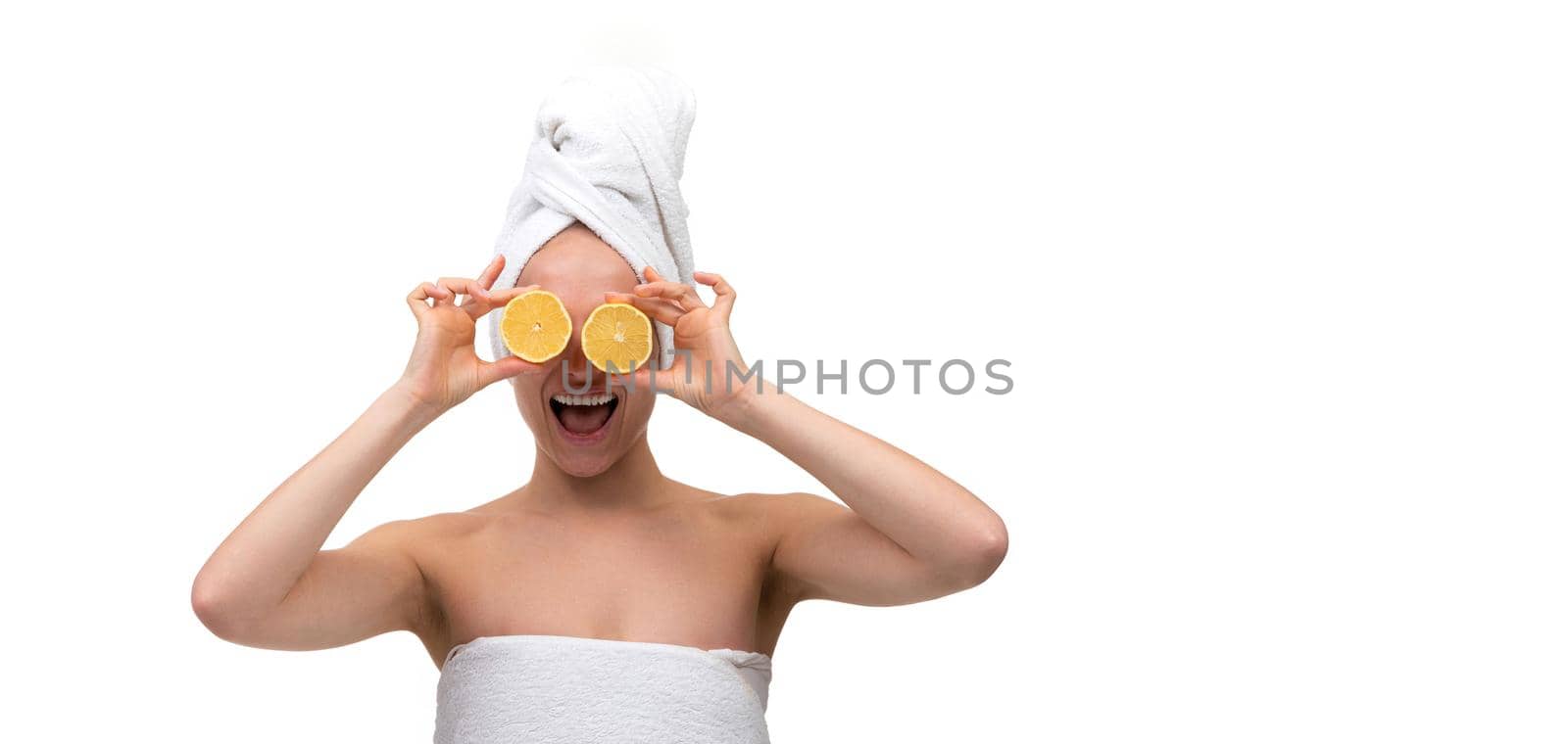 a cheerful middle-aged woman with well-groomed skin after a shower with a cut orange in her hands instead of eyes.