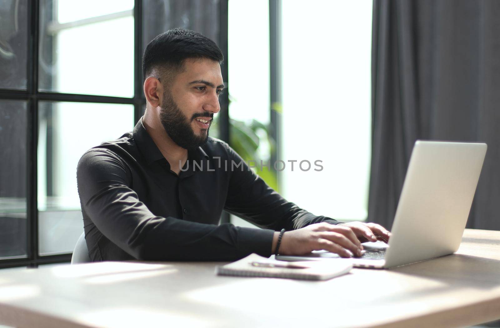 Focused young man wearing using laptop on keyboard, writing email or message by Prosto