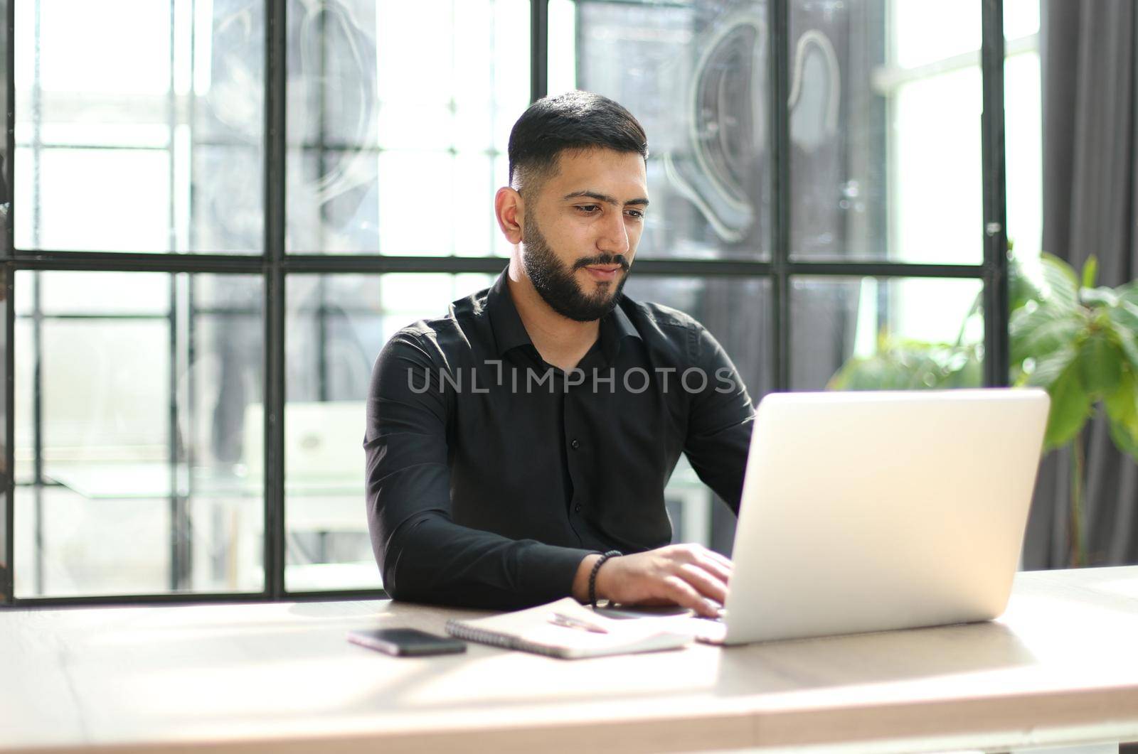 Focused young man wearing using laptop on keyboard, writing email or message by Prosto