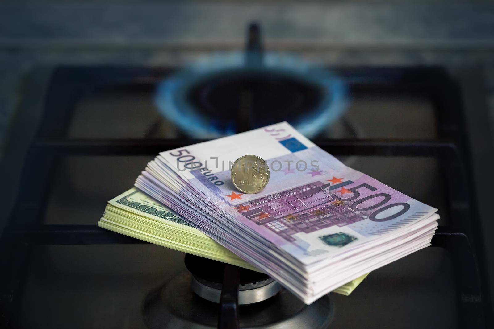 The Russian ruble stands on euro banknotes, near a lit gas stove at home. The concept of paying for gas in rubles. Close up. Copy space