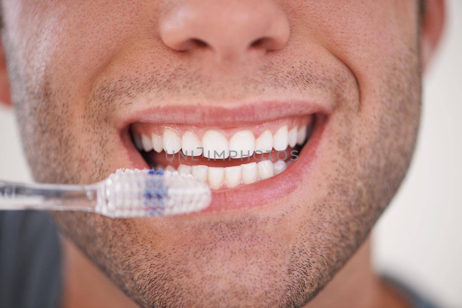 Keeping his teeth sparkly white. a man brushing his teeth