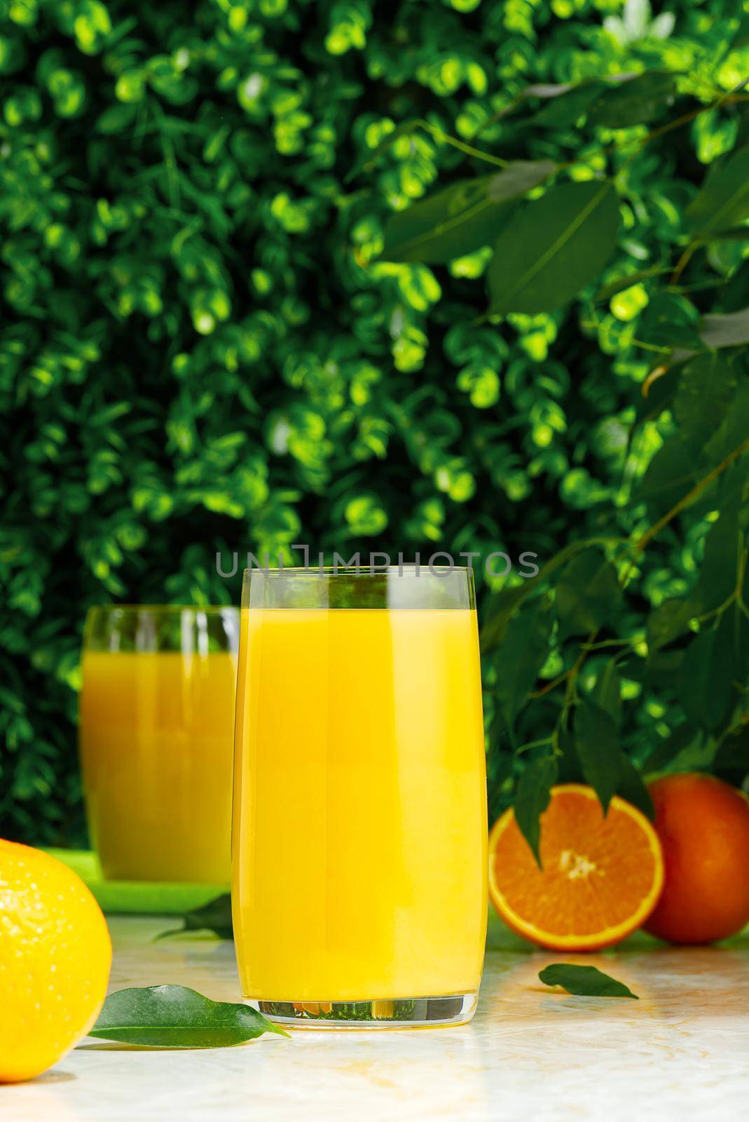glass of fresh orange juice with fresh fruits over a green background. fresh orange juice