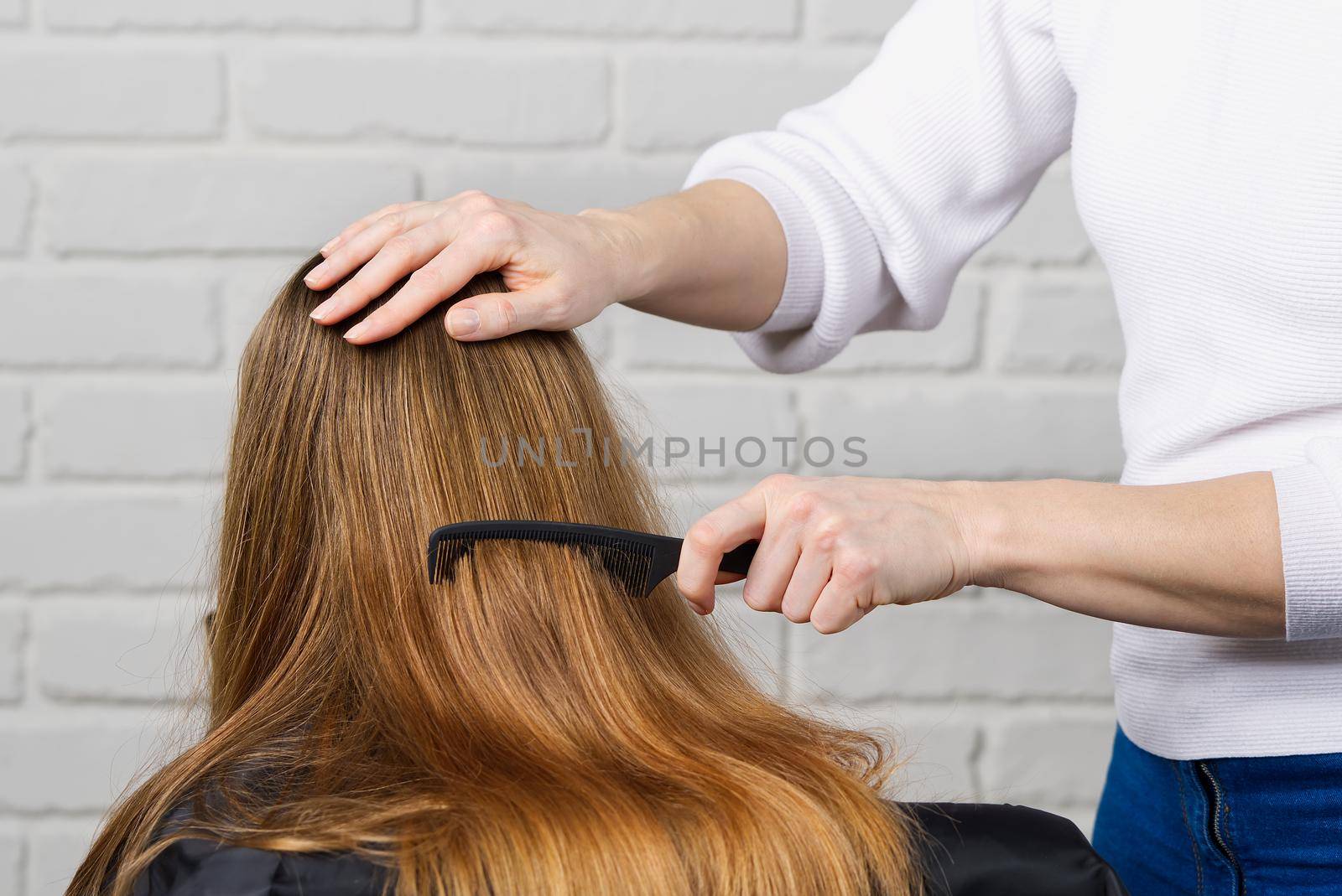 Beautiful girl with long hair. creating a hairstyle for a young unrecognizable girl. Hair styling process.