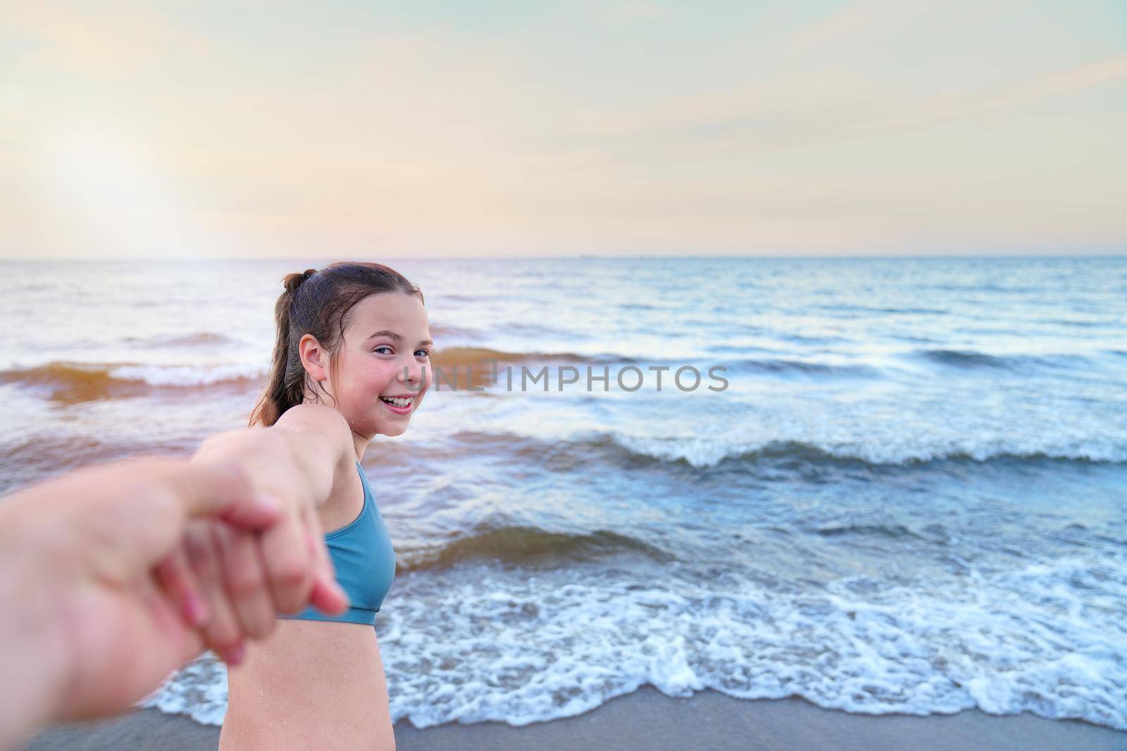 follow me swimming. Smiling girl standing at sea and invites you to swim, follow me travel concept by PhotoTime