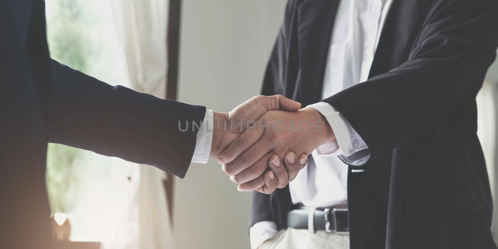 Two confident business man shaking hands during a meeting in the office, success, dealing, greeting and partner concept. by wichayada