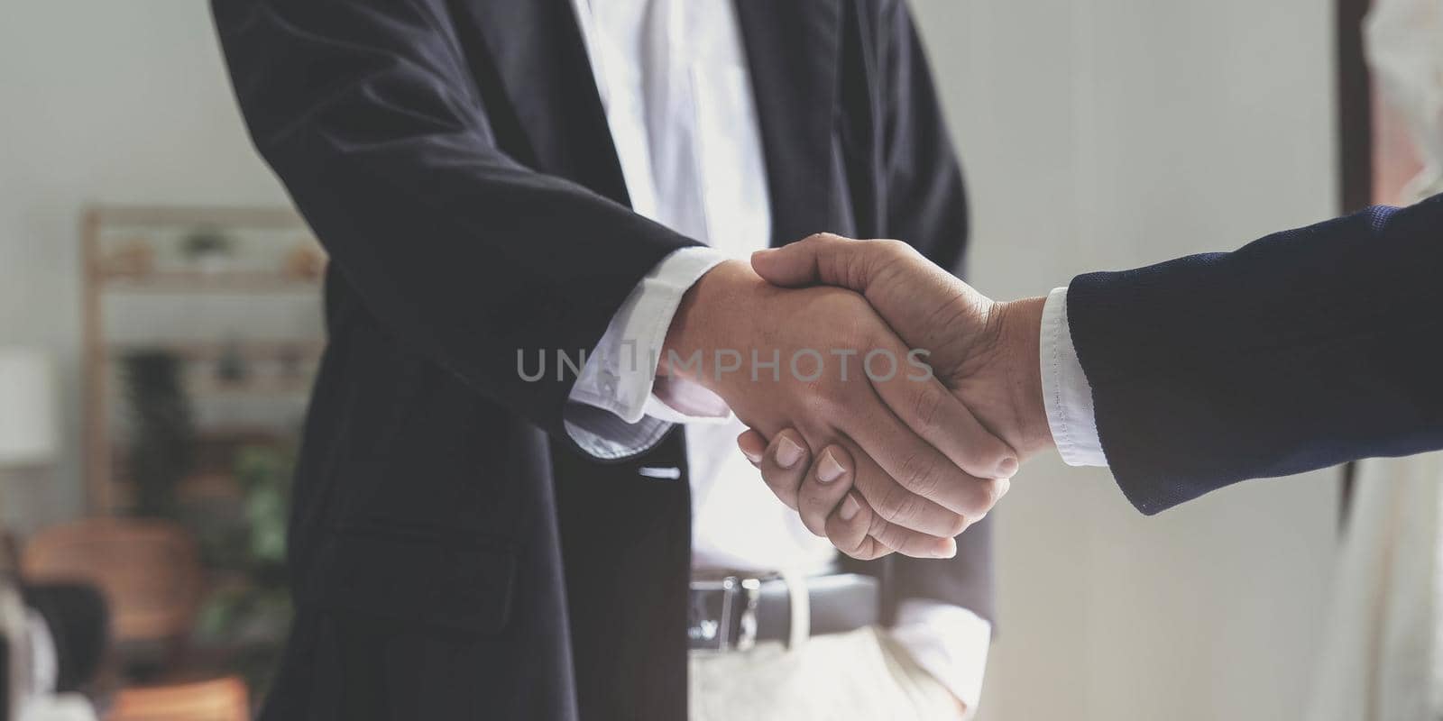 Two confident business man shaking hands during a meeting in the office, success, dealing, greeting and partner concept. by wichayada