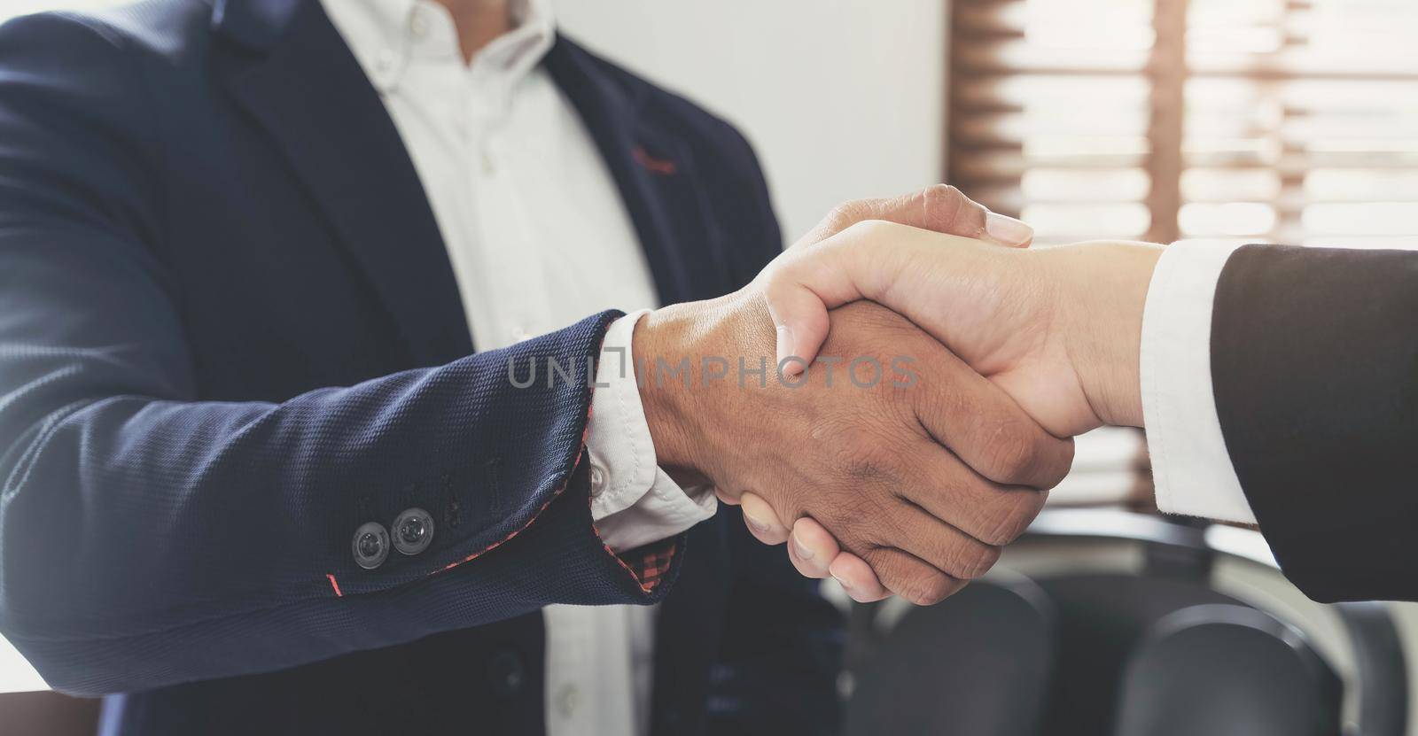 Two confident business man shaking hands during a meeting in the office, success, dealing, greeting and partner concept. by wichayada