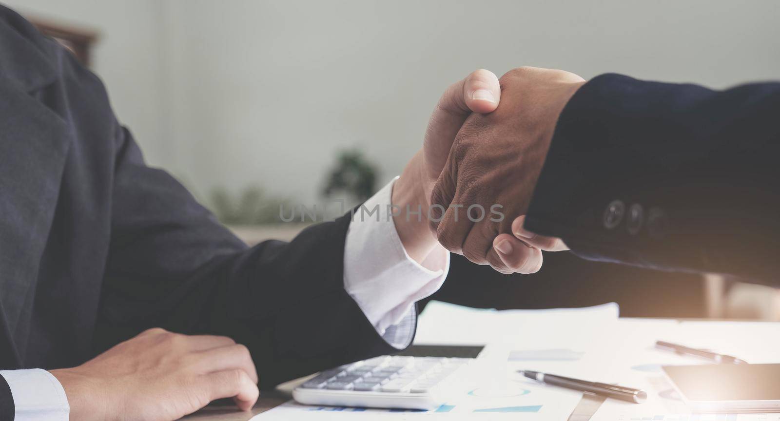 Two confident business man shaking hands during a meeting in the office, success, dealing, greeting and partner concept. by wichayada