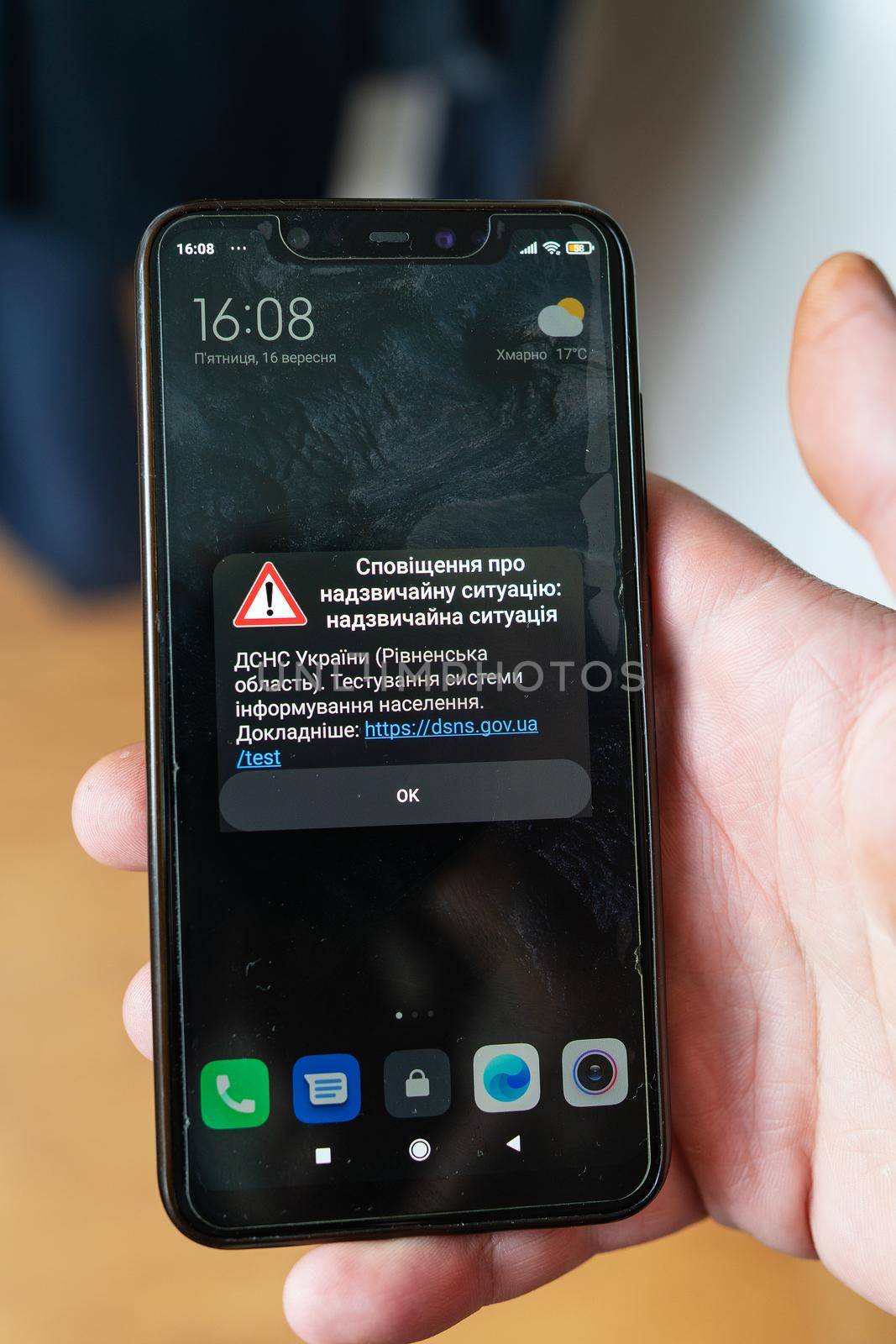 Rivne, Ukraine - September 16, 2022: Emergency notification from the State Emergency Service of Ukraine to smartphone. Girl hold mobile phone with alarm alert for Ukraine from DSNS during martial law.