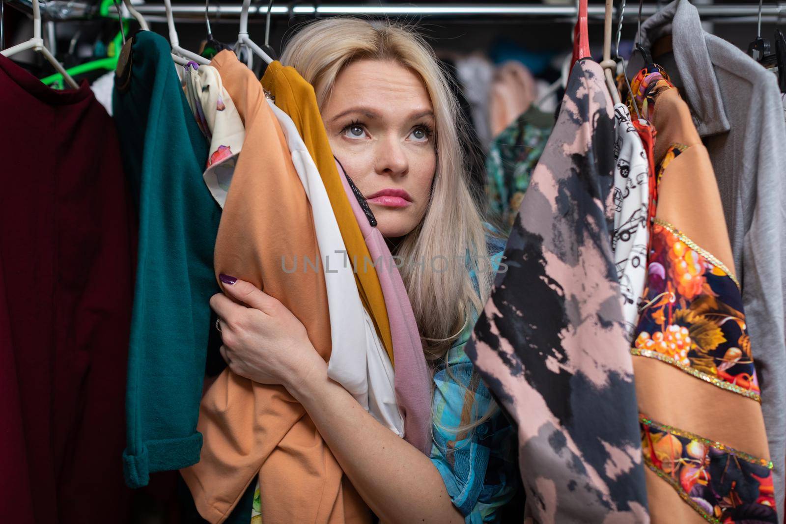 Woman dreamy while shopping for clothes. A blonde woman full of nostalgia while looking at a new clothing collection. She hugs the clothing.