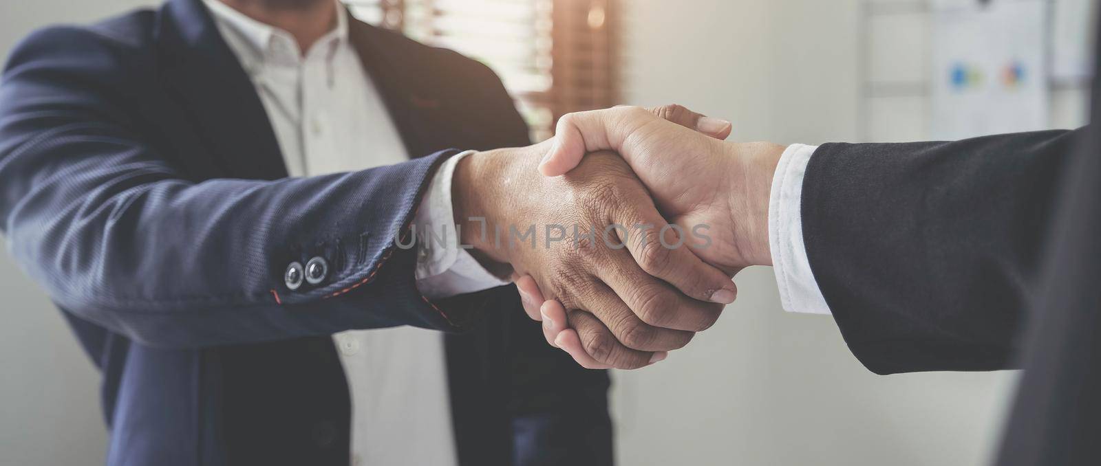 Two confident business man shaking hands during a meeting in the office, success, dealing, greeting and partner concept. by wichayada