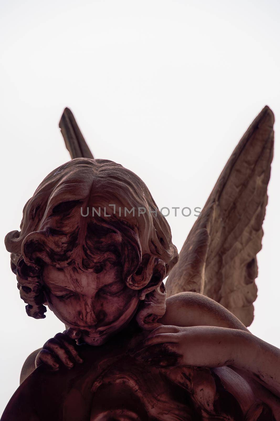 Statue figure of an angel with wings, against a white background.