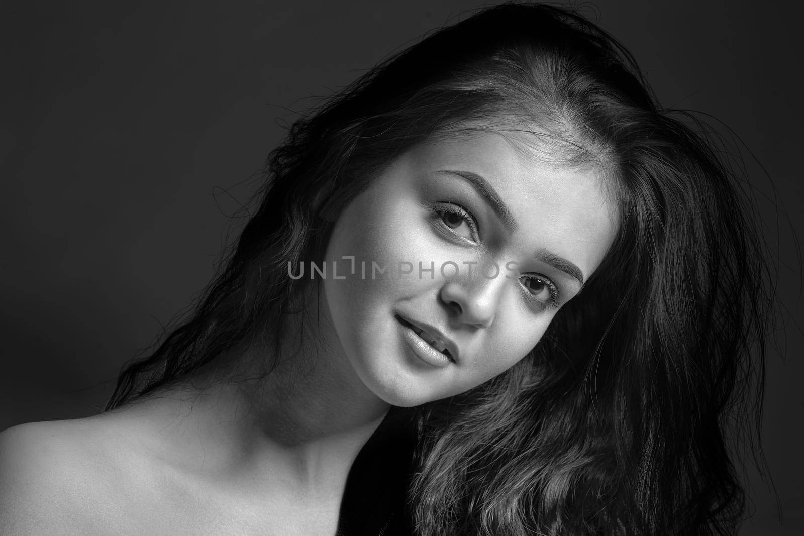 Monochrome portrait of a young attractive woman in the studio on a dark background.