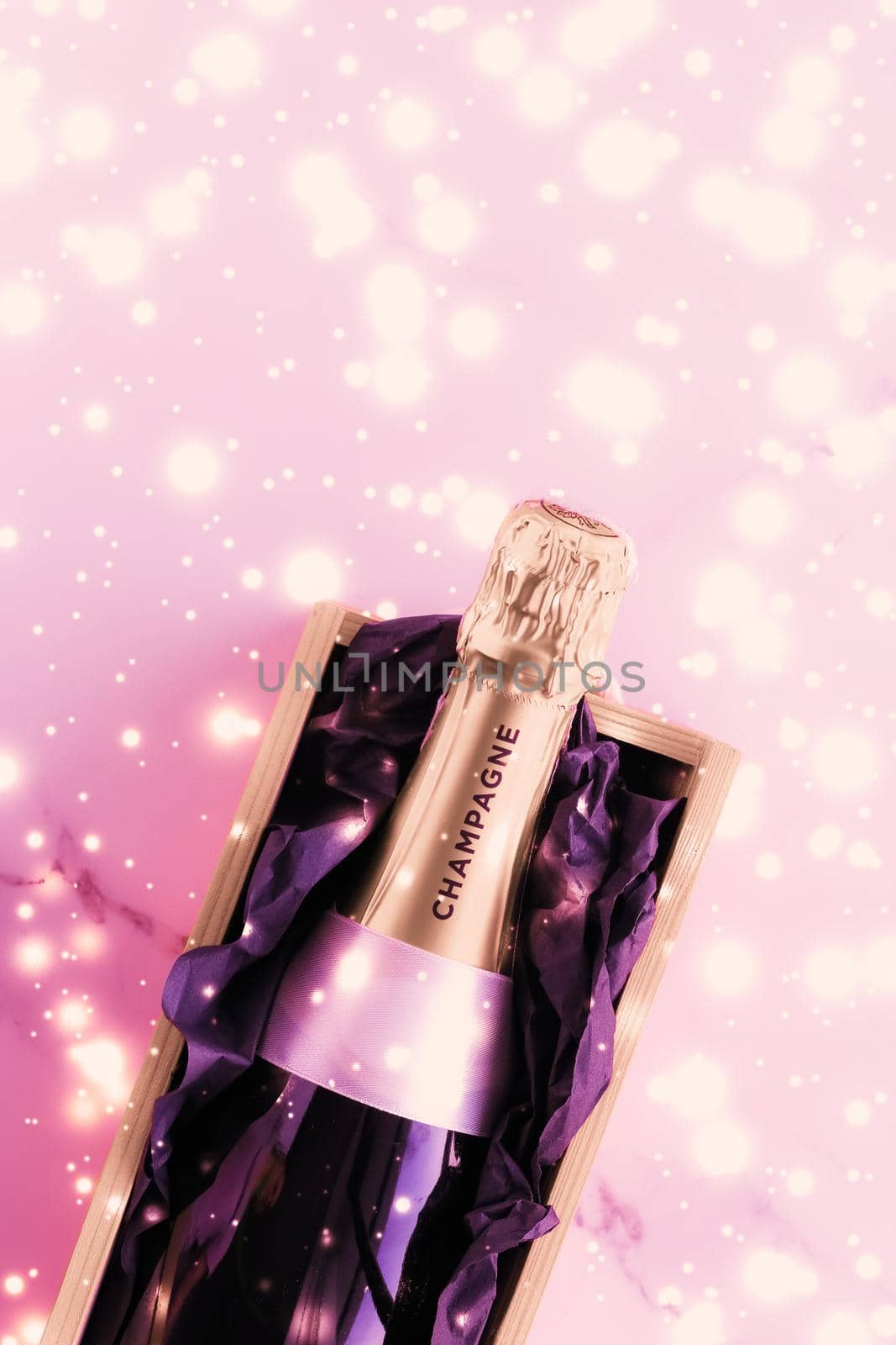 Celebration, drinks and branding concept - Champagne bottle and gift box on pink holiday glitter, New Years, Christmas, Valentines Day, winter present and luxury product packaging for beverage brand