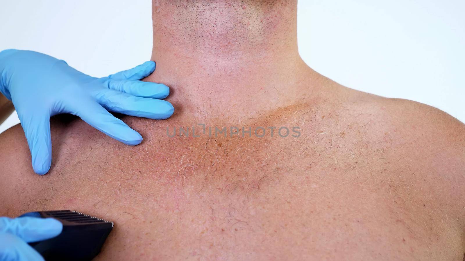 Close-up, cosmetologist female hands in gloves haircut body hair of a Naked hairy Man, his chest, Torso, whole body with a clipper, electric razor, trimer. on white background. High quality photo