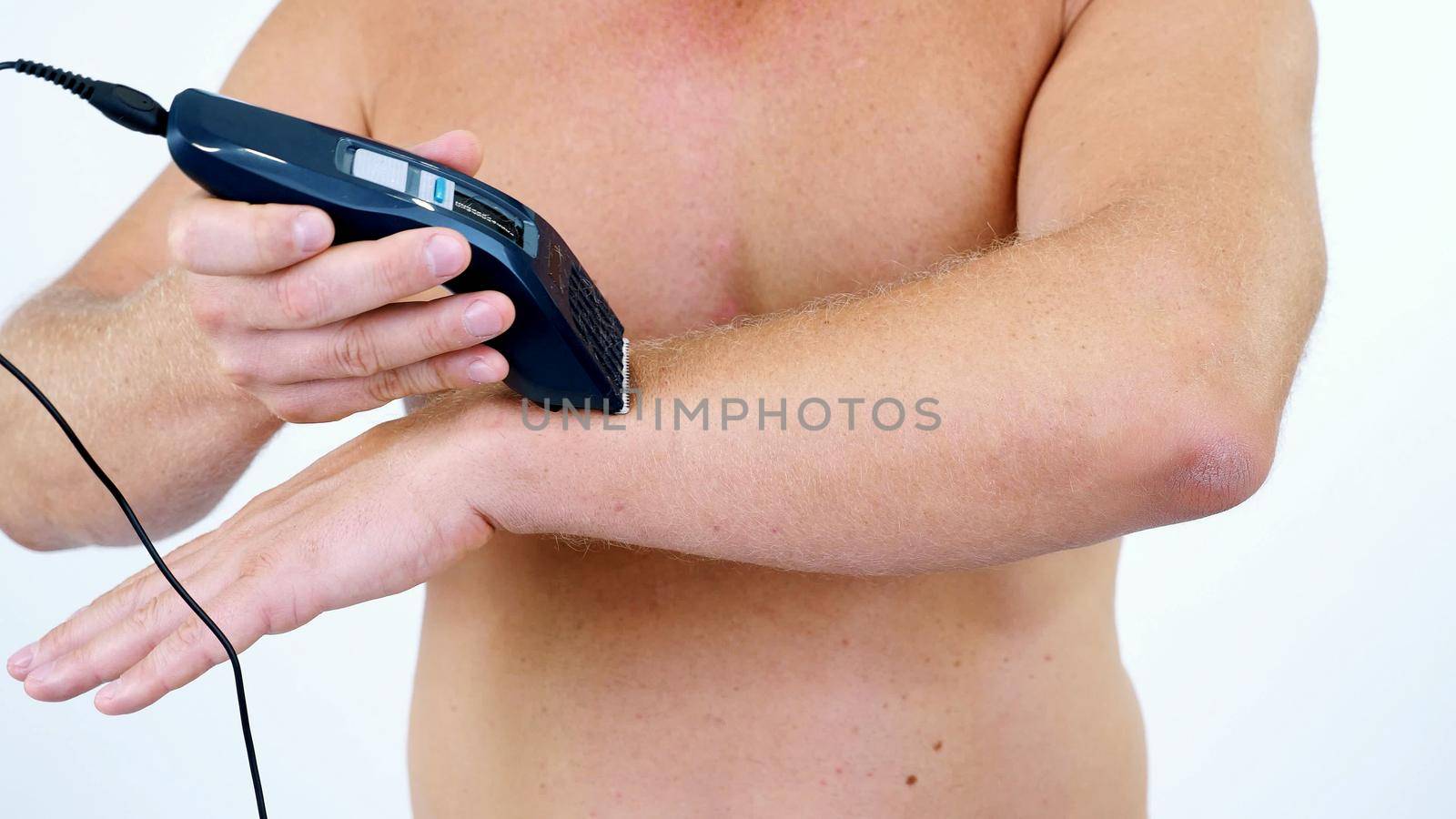 Close-up of a very hairy Man haircut body hair on his whole body, hands by himself with a clipper, electric razor, trimer. isolated on white background. Naked man shaves his body. High quality photo