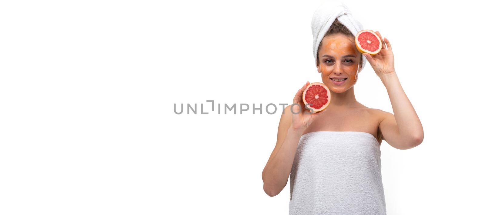 widescreen photo of a middle-aged woman after bathing procedures on a white background with an orange grapefruit in her hands.