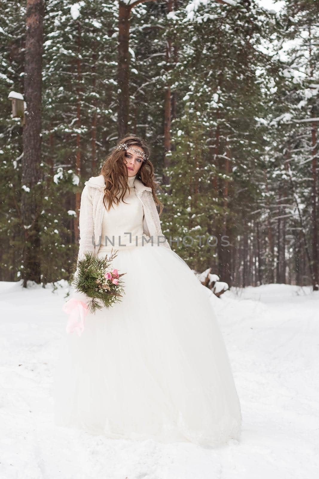 Beautiful bride in a white dress with a bouquet in a snow-covered winter forest. Portrait of the bride in nature by Annu1tochka