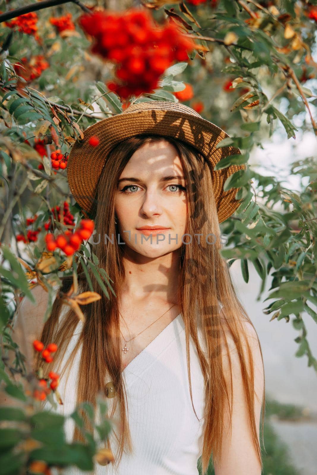 A beautiful blonde girl in a hat with long hair, on a walk in the autumn season. Portrait of a woman at a rowan tree by Annu1tochka