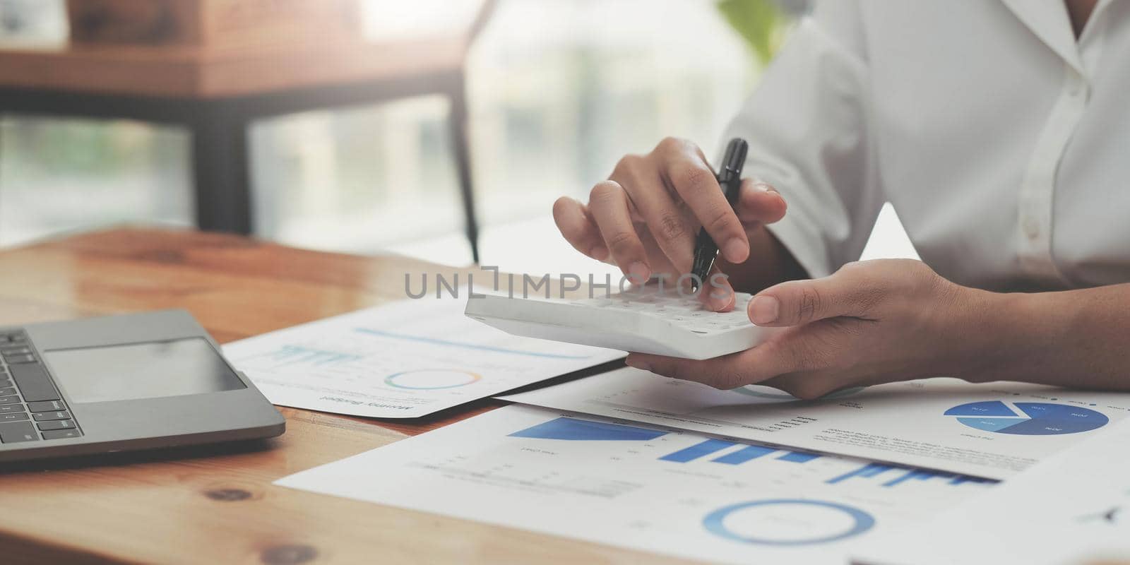 woman hand using calculator, working with graph chart and analyzing business strategy, financial statistic, sitting at desk office, vertical view. by wichayada