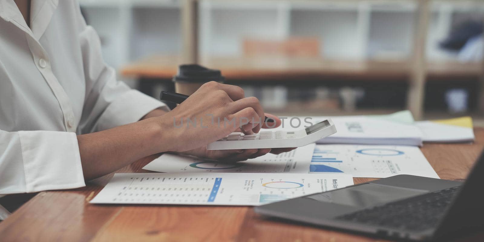 woman hand using calculator, working with graph chart and analyzing business strategy, financial statistic, sitting at desk office