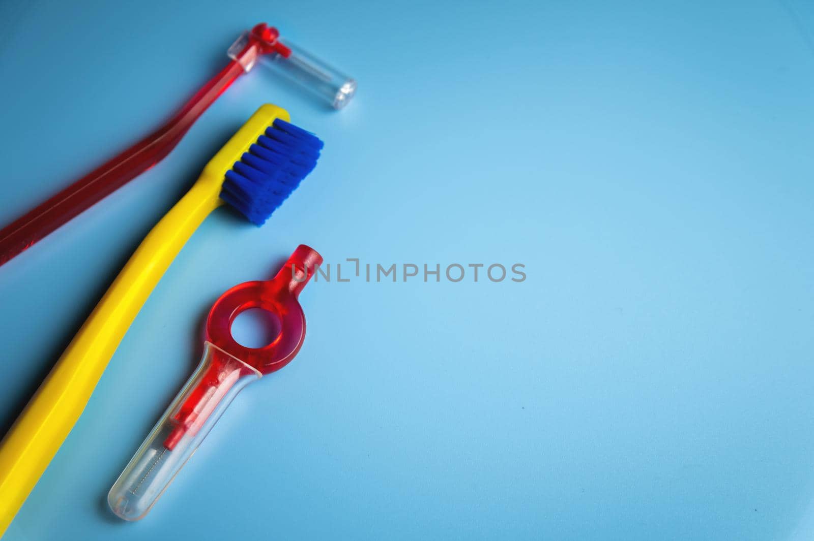 a bright toothbrush, a red orthodontic interdental brush lie on a blue background, no people.