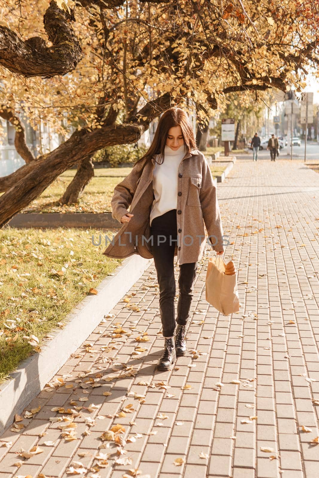 A stylish brunette woman walks around the autumn city. The season is autumn.