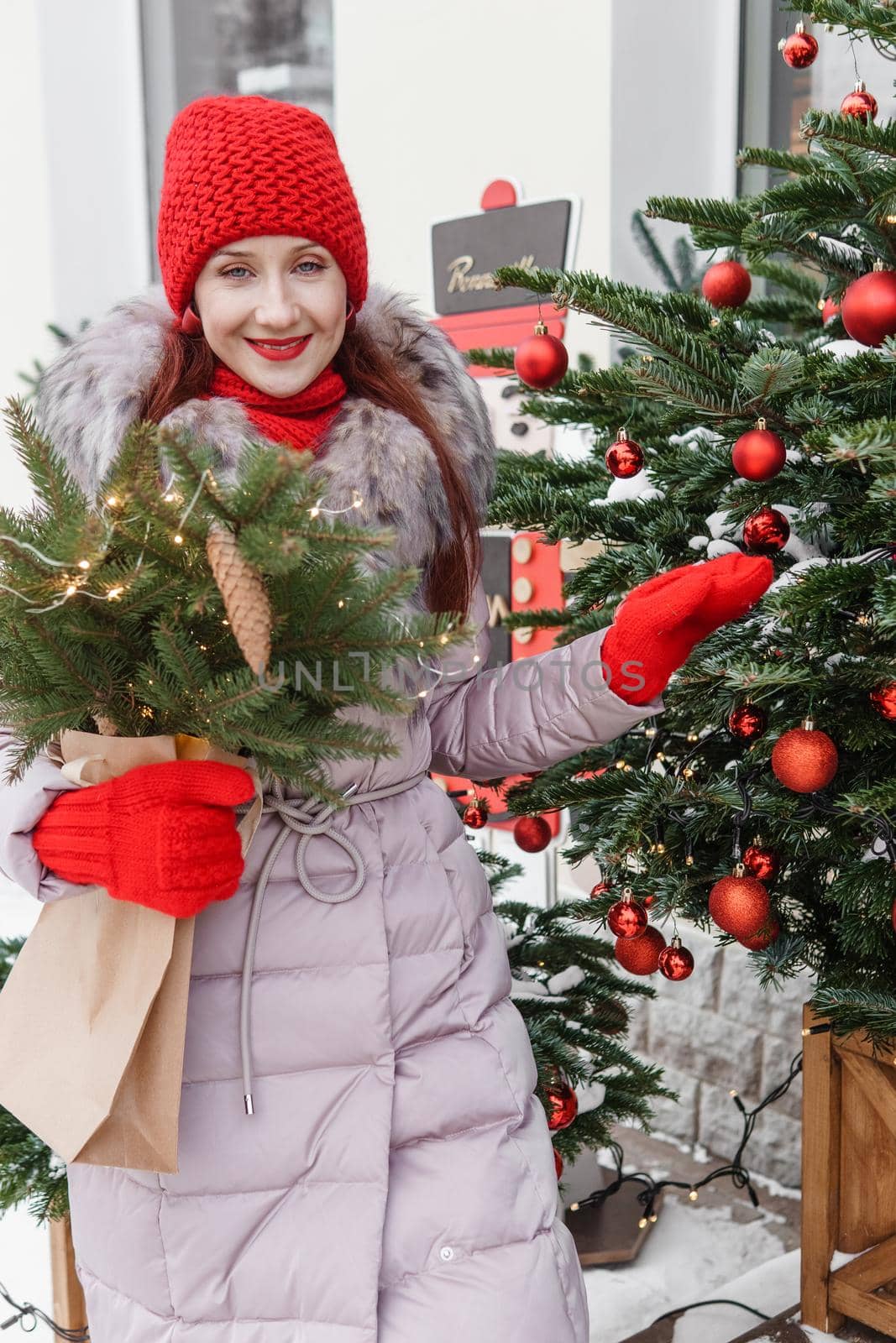 A bright woman in winter clothes walks around the city decorated for Christmas. Lifestyle in the winter season.