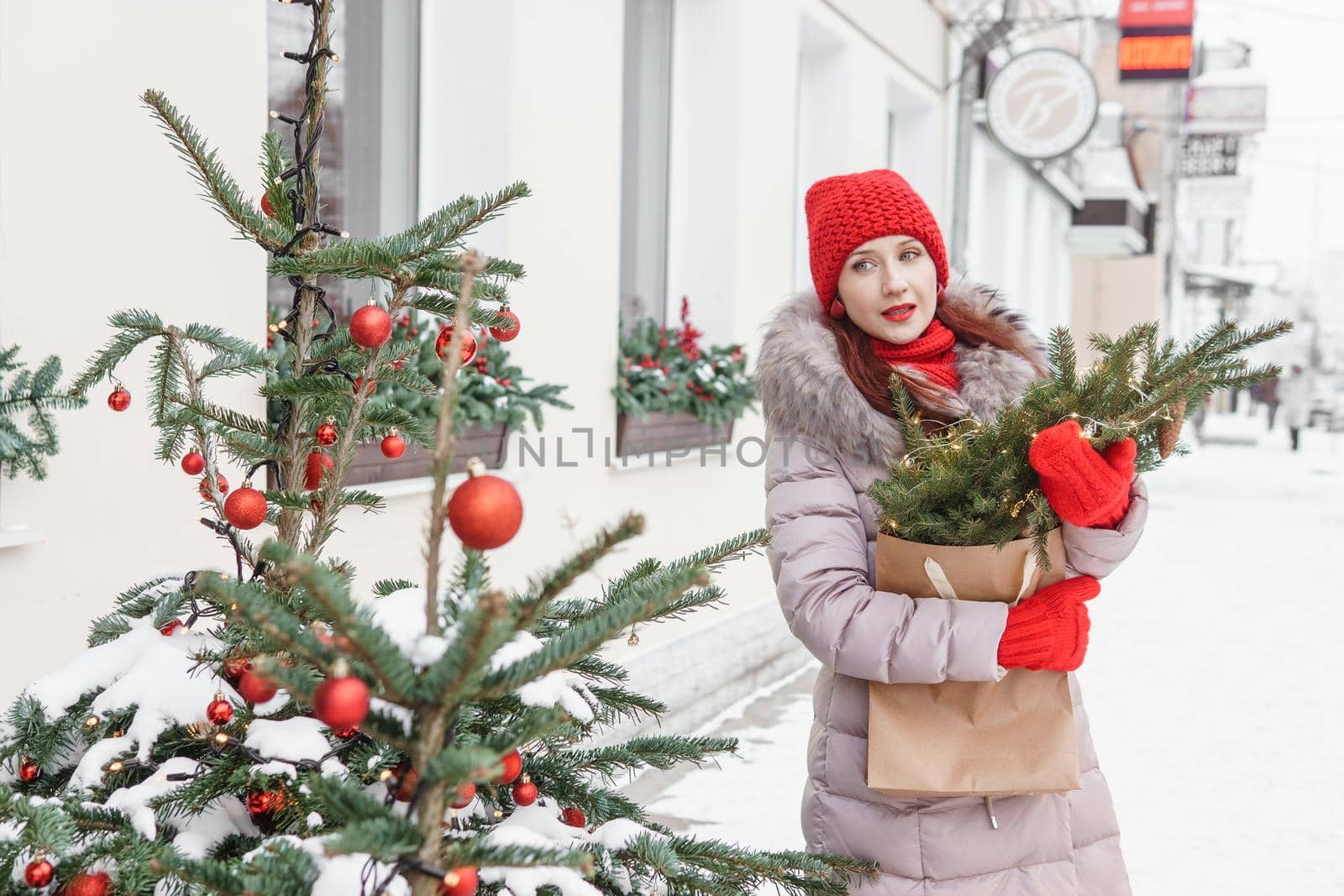 A bright woman in winter clothes walks around the city decorated for Christmas. Lifestyle in the winter season.