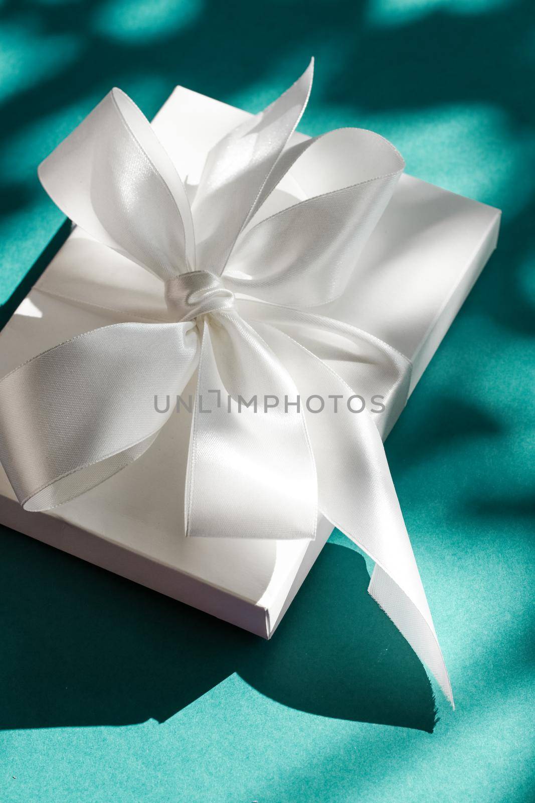 Anniversary celebration, shop sale promotion and bridal surprise concept - Luxury holiday white gift box with silk ribbon and bow on emerald green background, luxe wedding or birthday present
