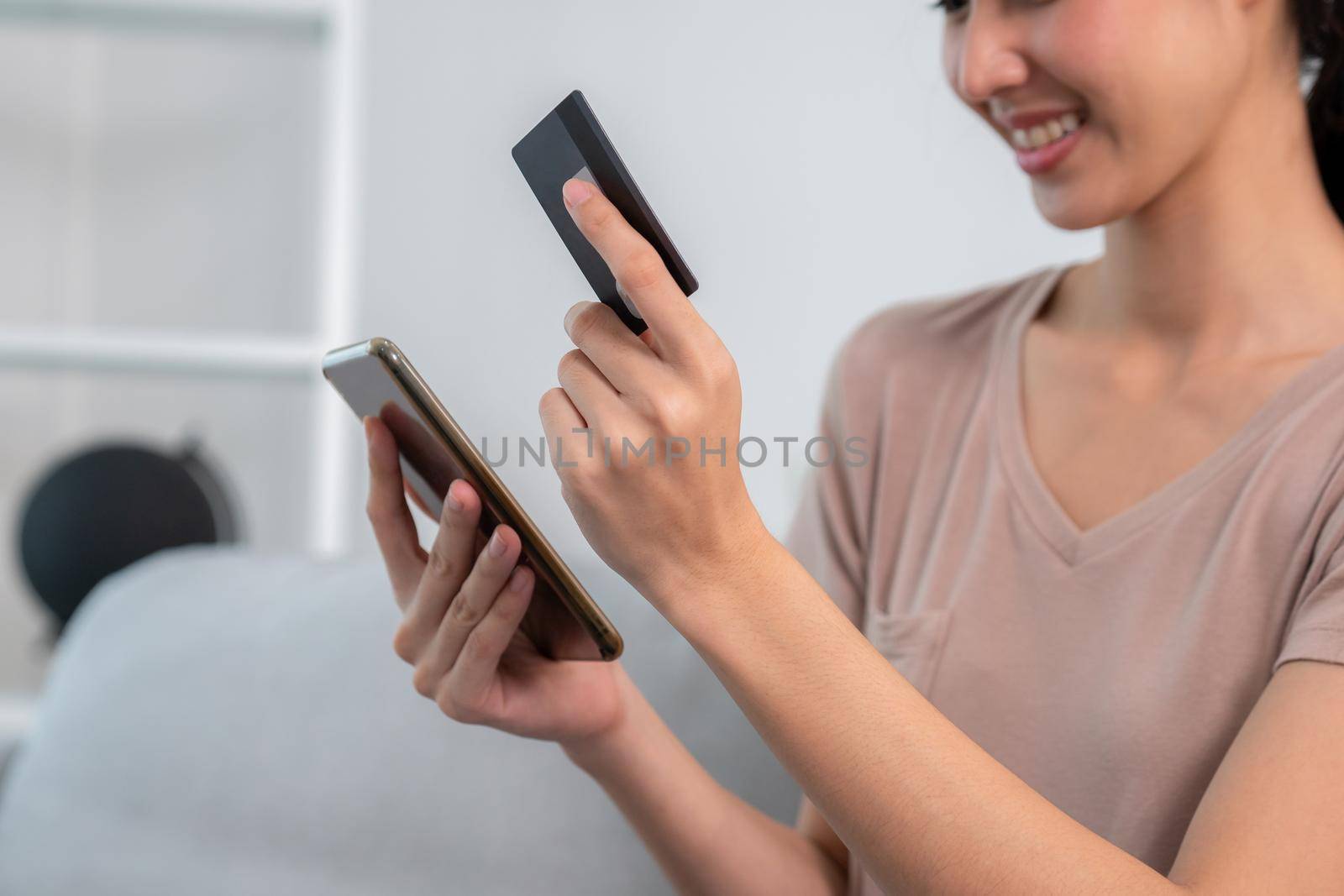 Contented young woman eagerly makes an online purchase using her smartphone. E-commerce business, online purchasing.