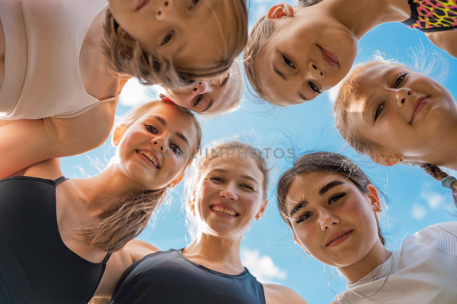 Group of children and young girls with female coach in the circle as friendship.