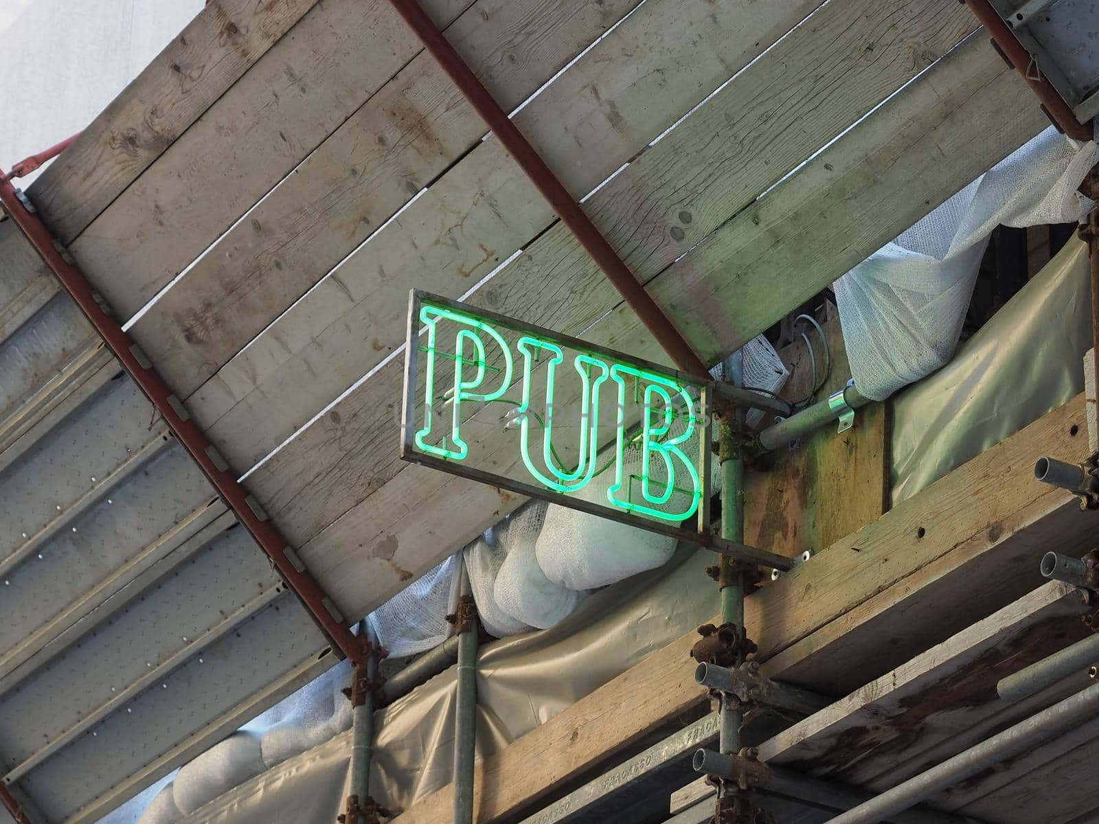 green neon light pub sign on a building with scaffolding