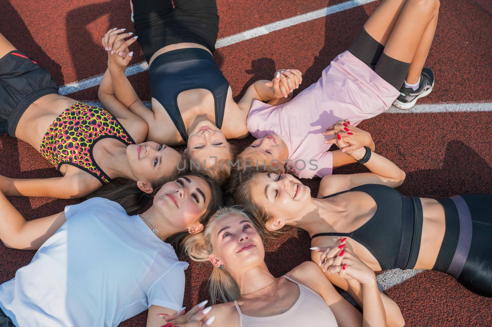 Group of children and young girls with female coach in the circle as friendship.