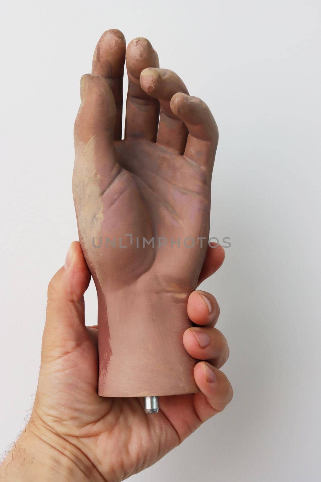 A man's hand holds an artificial plastic hand on a white background. by gelog67