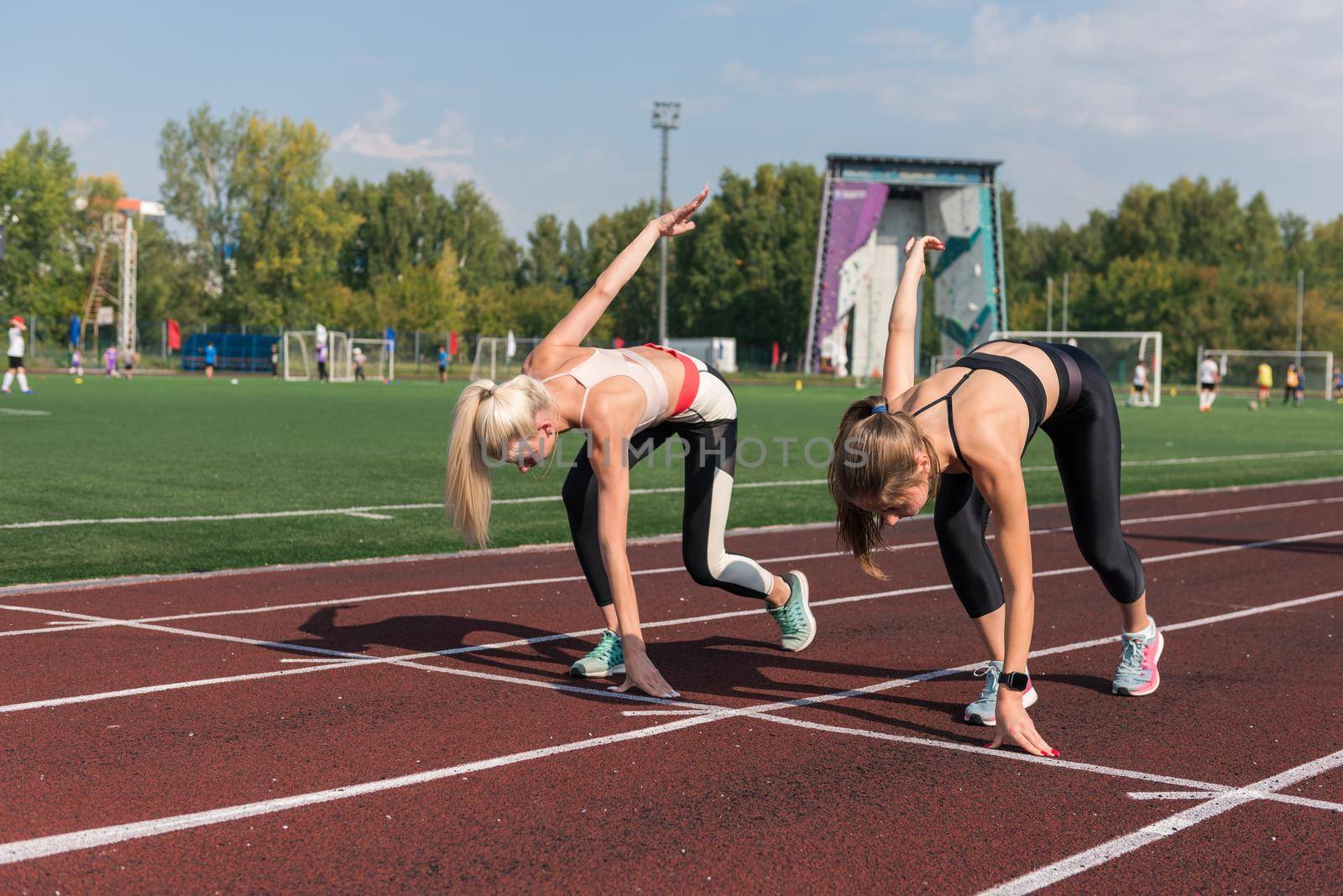 Two athlete young woman runnner on the start at the stadium outdoors