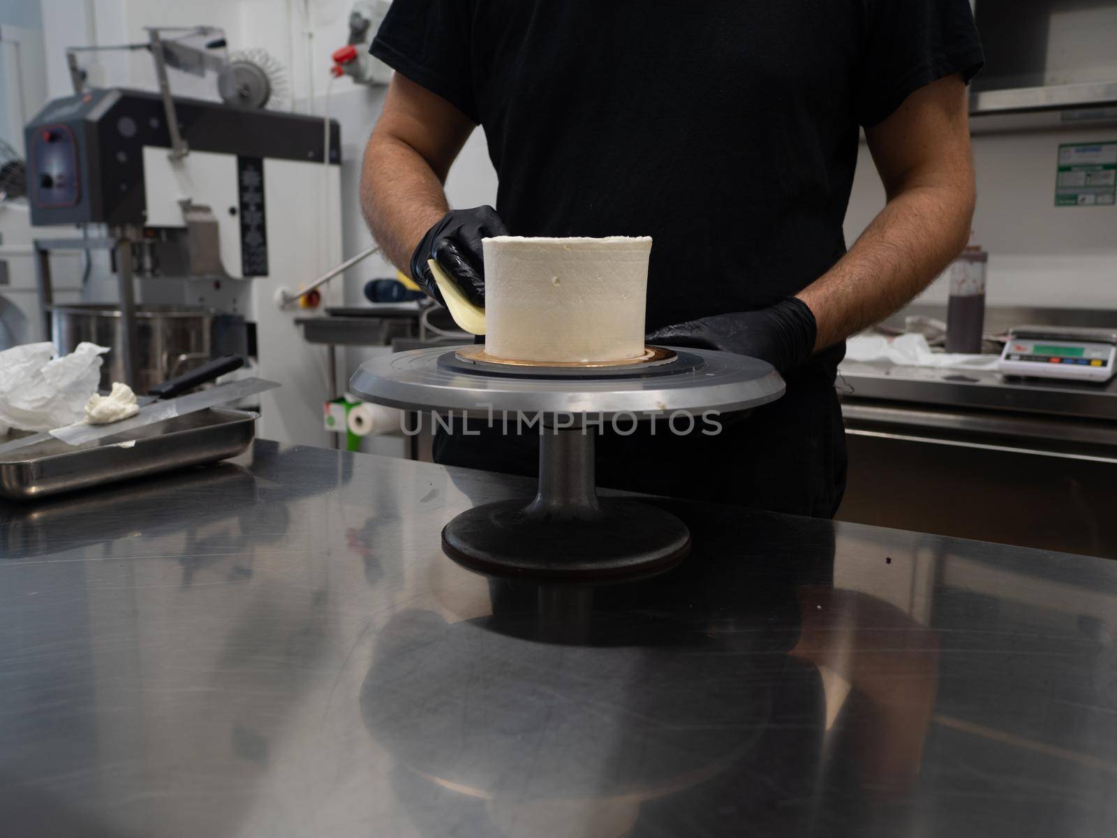 Decorator using spatula and scraper to smooth buttercream on a frosted cake