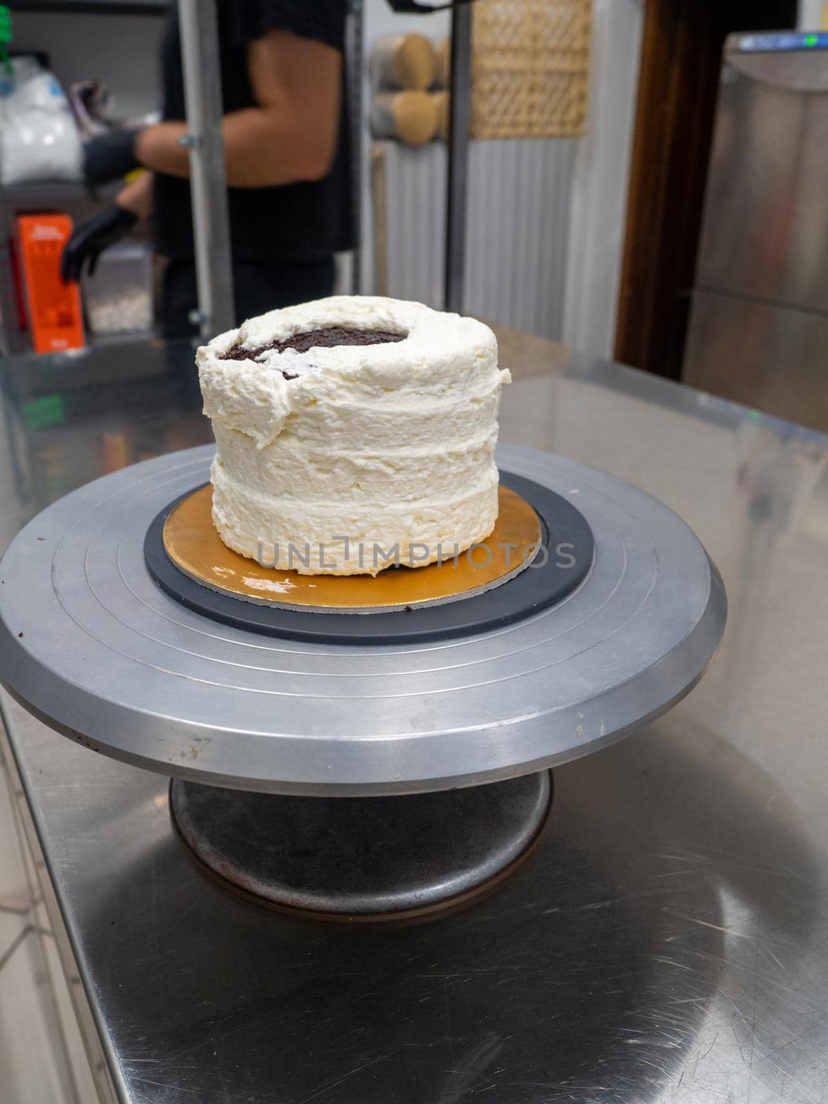 Decorator using spatula and scraper to smooth buttercream on a frosted cake