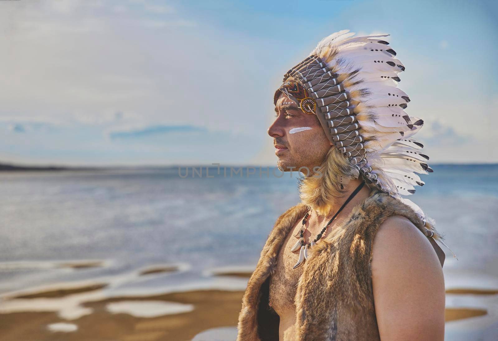 man in traditional Native American clothing near the sea.