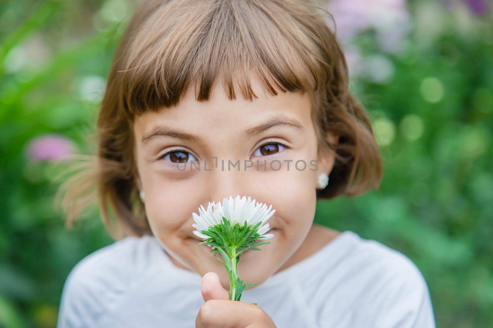 A child smells a flower in the garden. Selective focus. Kid.