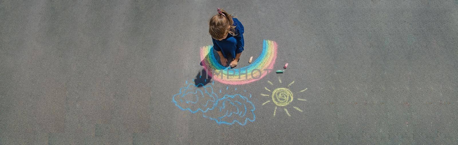 child draws with chalk on the pavement. Selective focus. by yanadjana