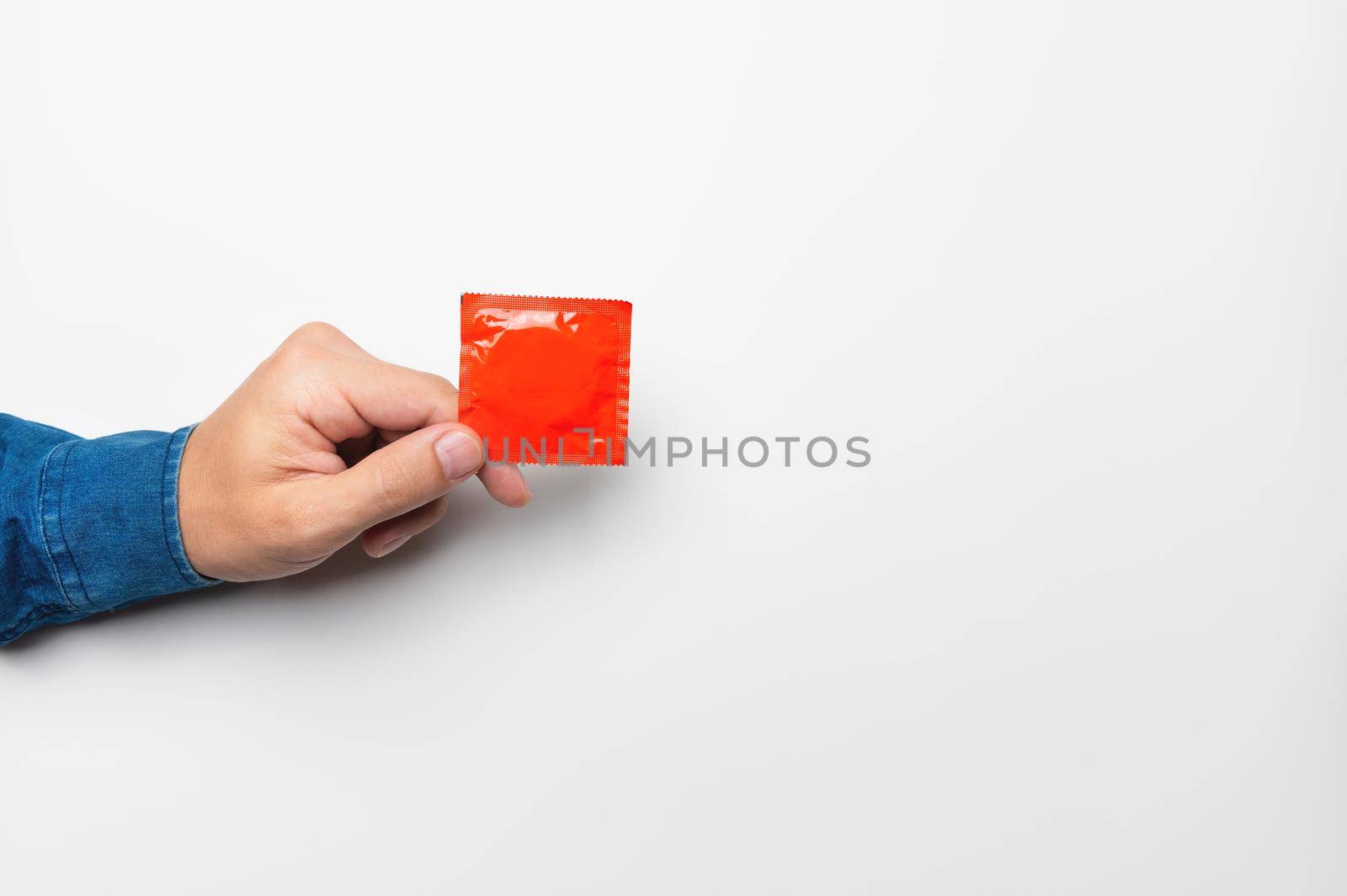 hand with a condom in a red package on a white background, mockup for your advertising.