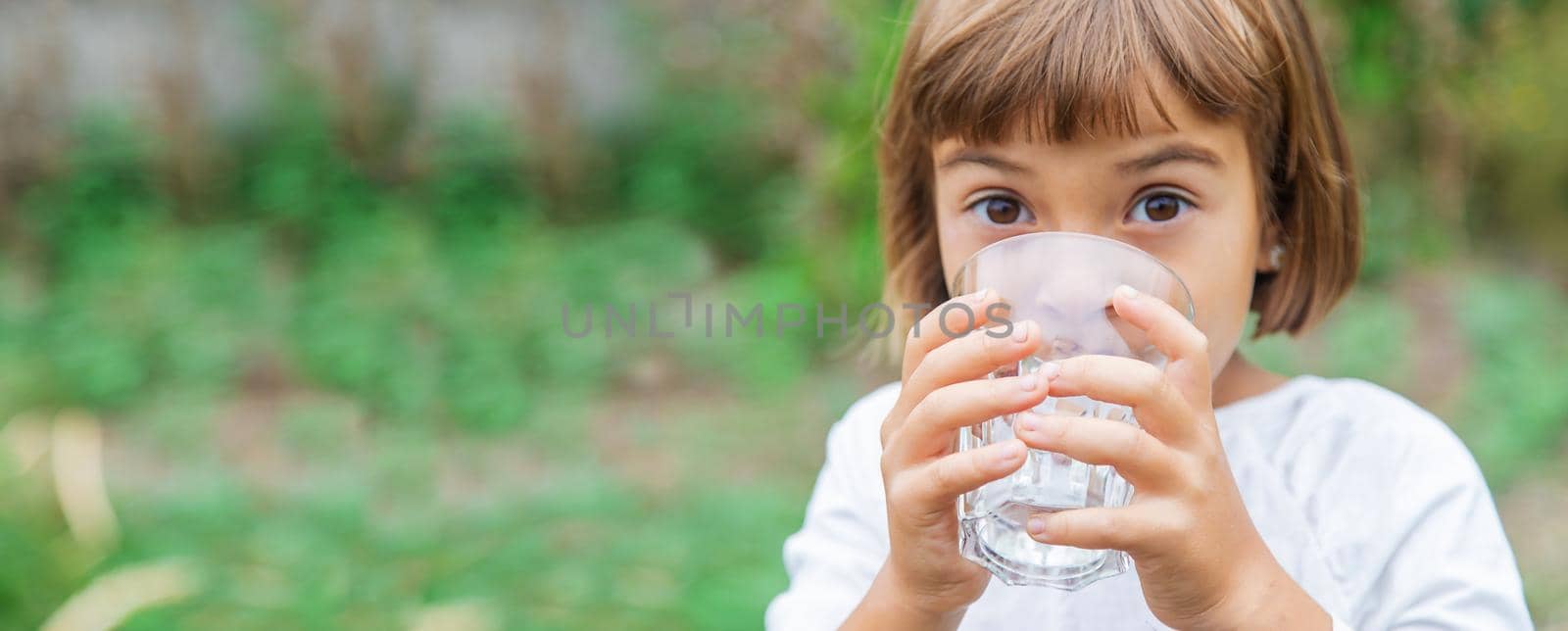 child drinks water from a glass. Selective focus. Kid.