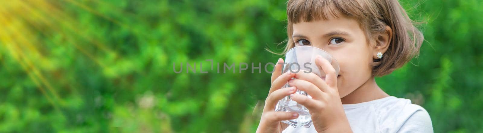 child drinks water from a glass. Selective focus. Kid.