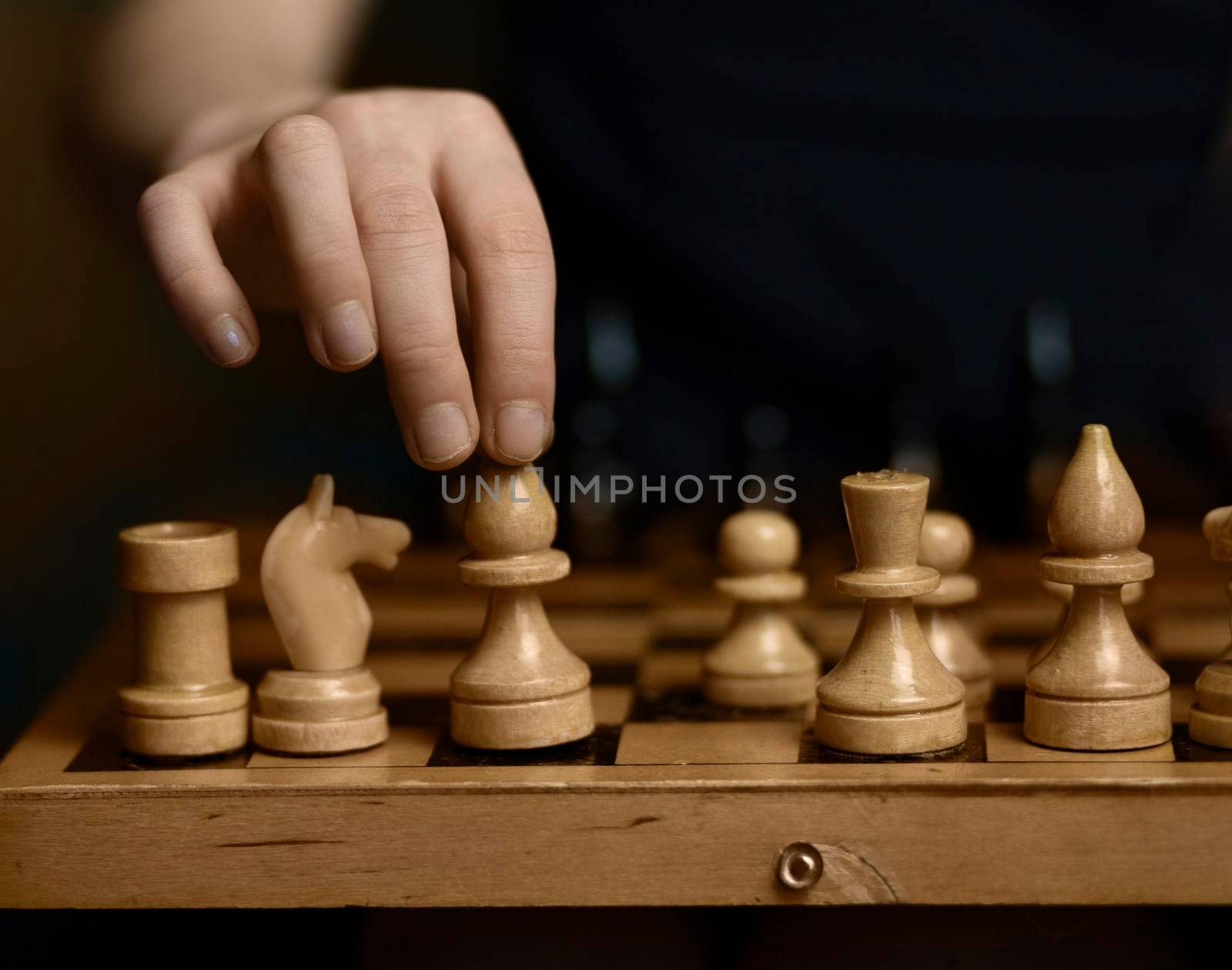 chess board white and black pieces a child's hand takes a chess piece of a white elephant with children's fingers. High quality photo