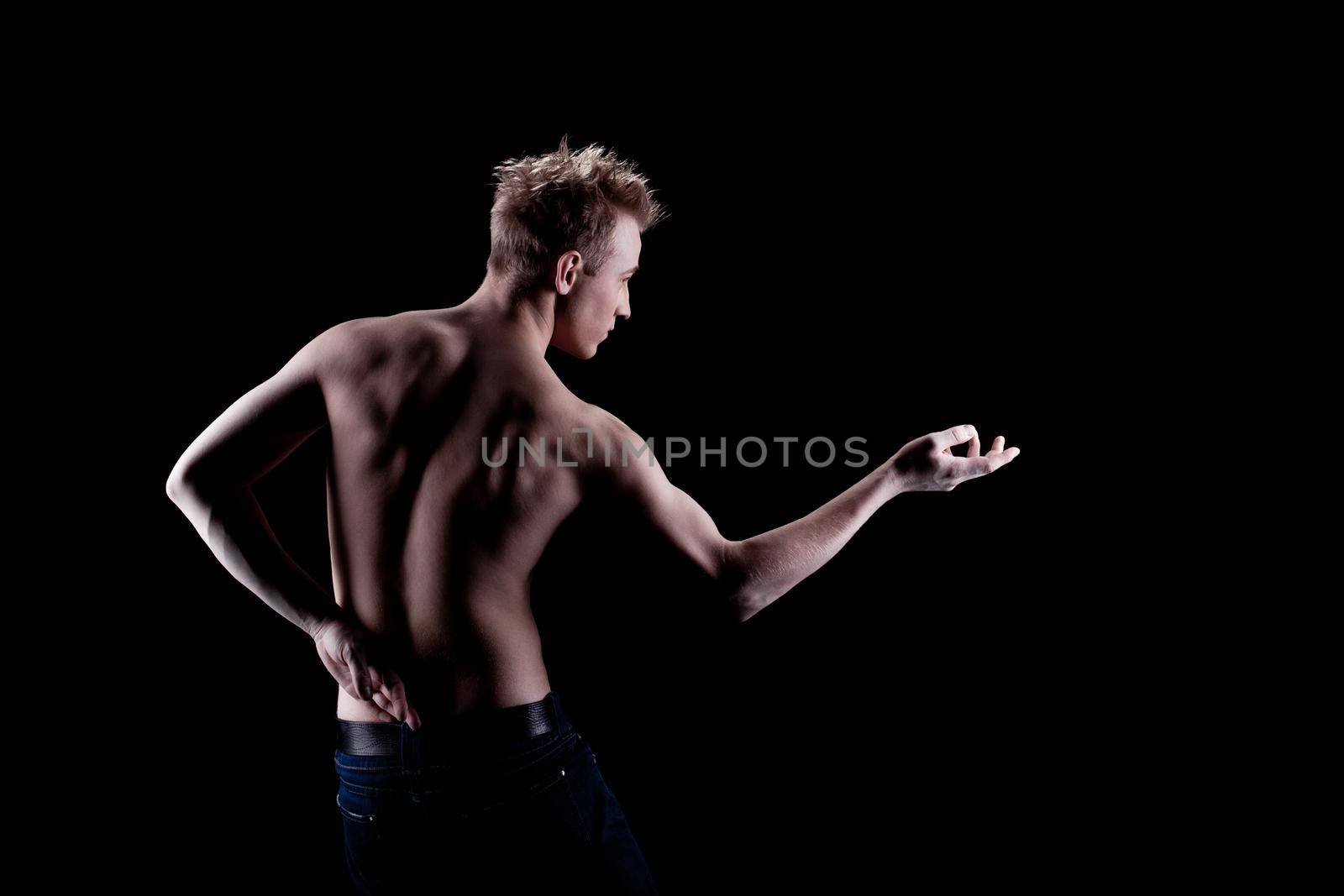 Young man naked torso in jeans in dark