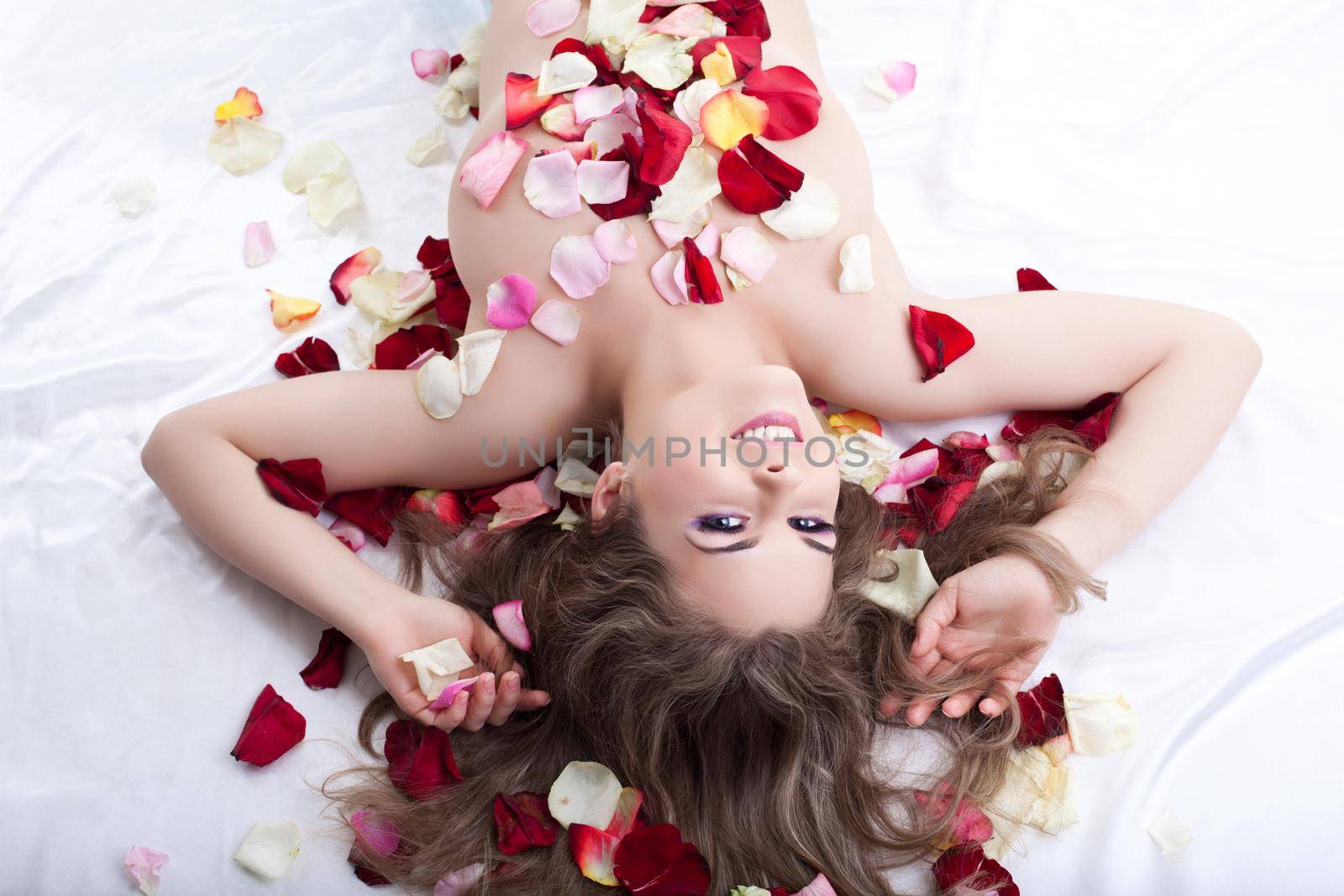 Beautiful woman lying in bed in rose petals