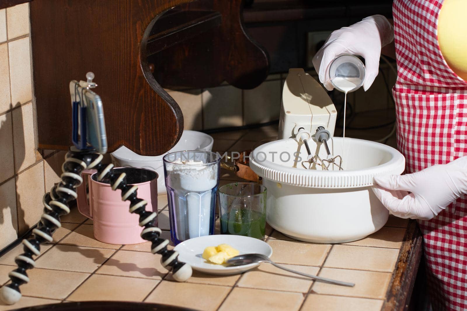 a woman prepares spinach muffins step by step, mixes the ingredients with a mixer, records a video on a mobile phone for social networks, add cream to dough. High quality photo